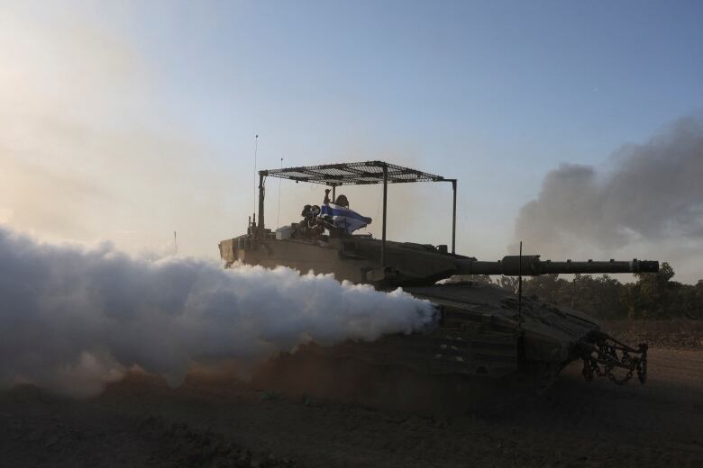 Smoke billows from a tank as it maneuvers along a road.