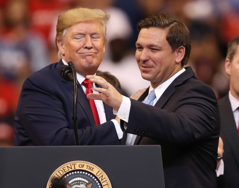 People greet each other at a lectern.