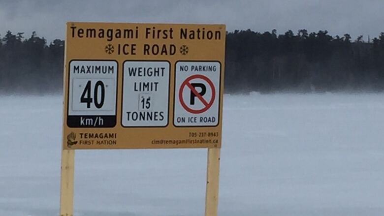 A sign on a frozen lake with trees in the background reads 'Temagami First Nation ice road' with some information about loading and speed restrictions 