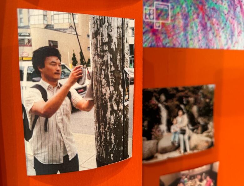 A young man with black hair, wearing a white short-sleeved shirt with dark stripes, puts up a poster on a pole.