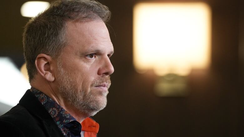 A man listens to a question from reporters.