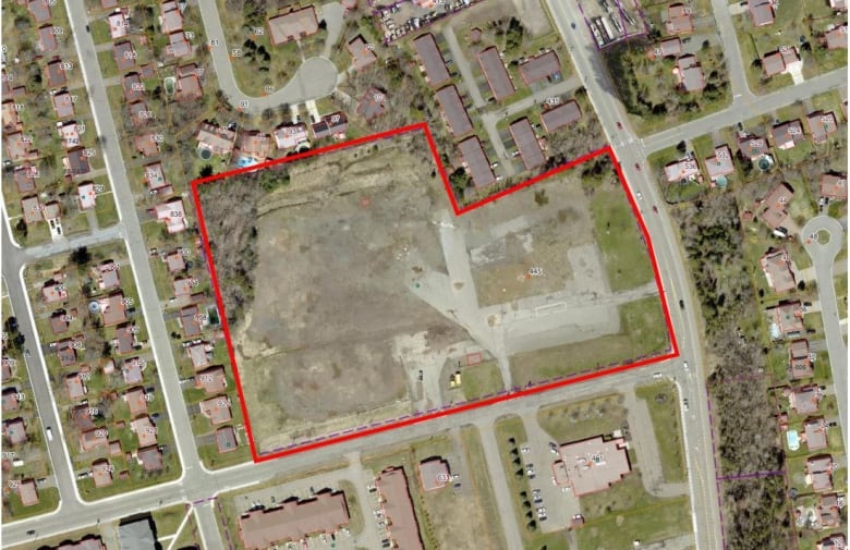 A satellite map showing residential streets with a empty parcel bounded by a red box. 