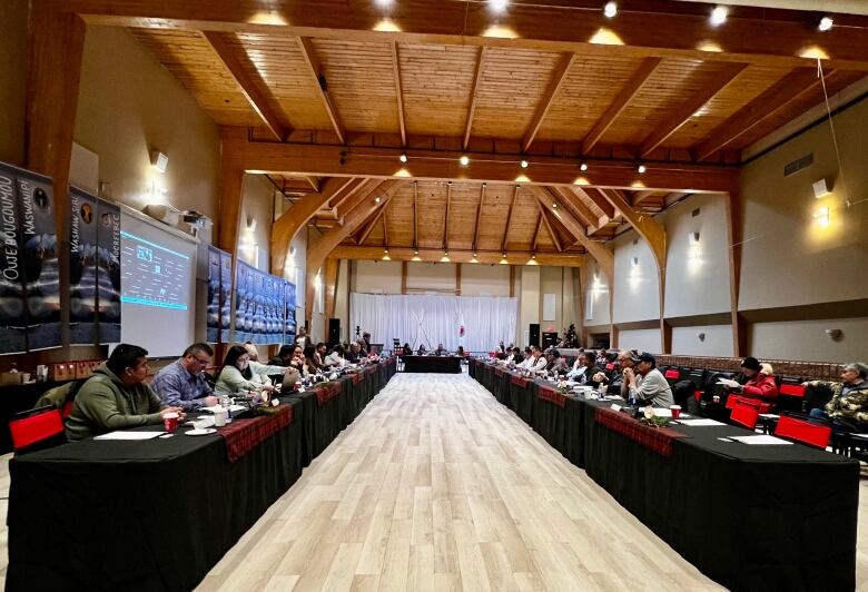 Two rows of wooden tables with Cree and Innu leaders meet in a large hall in Chisasibi.