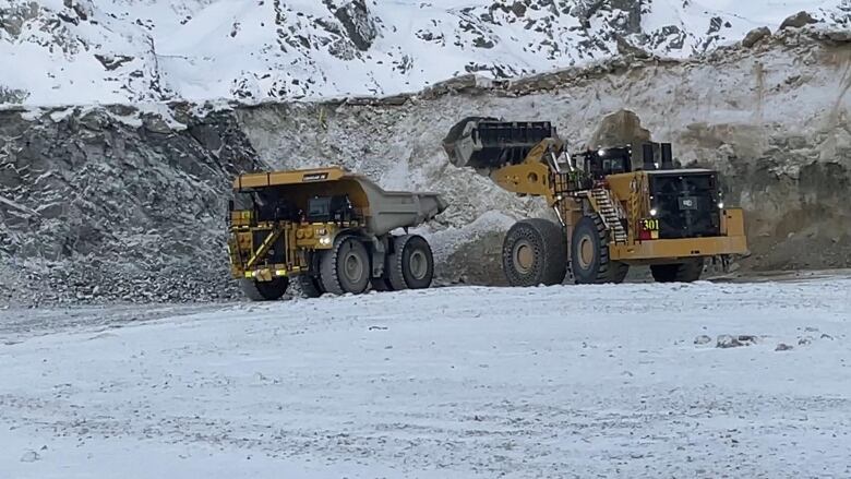 A yellow hauling truck with a yellow loader next to it.