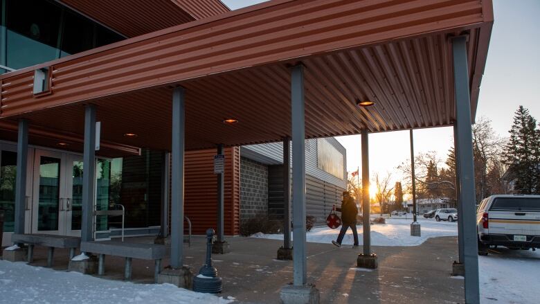 A person walks into a building with the sun in the background.