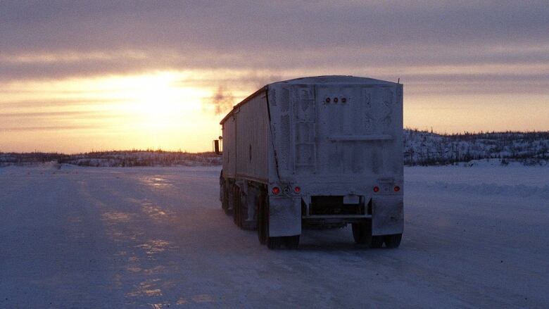 The back of a large transport truck driving over an icy road is shown.