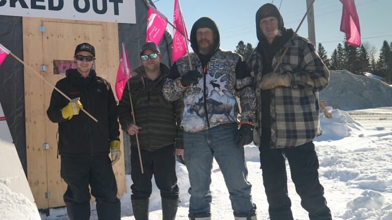 Four men on a picket line holding flags.