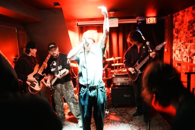 A band performs indoors under red light.