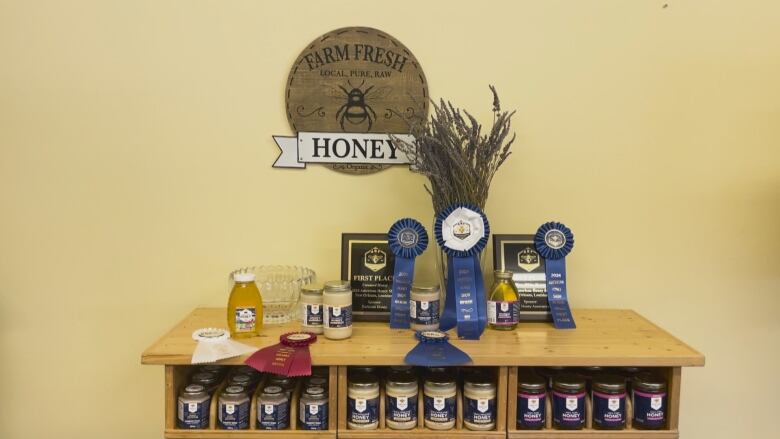 A desk cabinet with jars of honey, plaques and ribbons