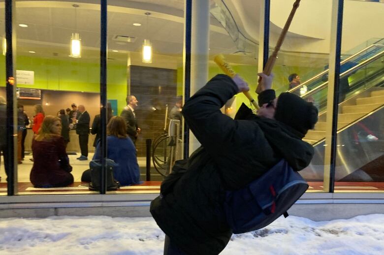 A man leaning back and blowing into a horn outside of a building