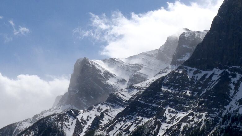 a mountain with snow is pictured against a blue sky.