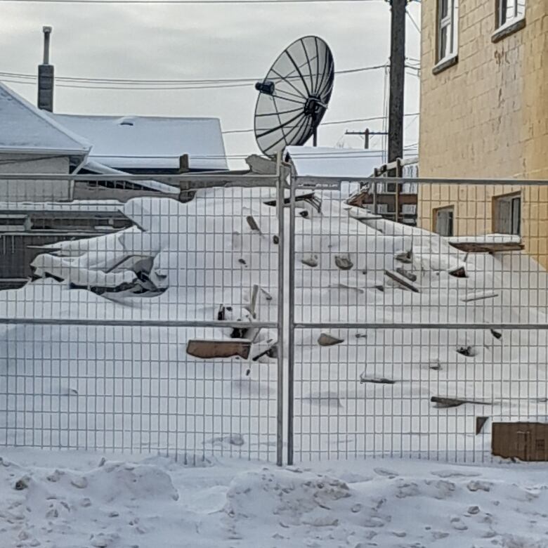 A pile of rubble can be seen behind a fence.