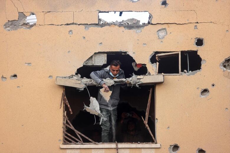 A person looks through the window of a heavily damaged building.