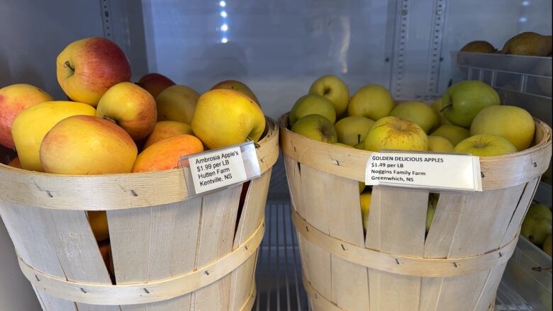 Two baskets full of apples in a commercial fridge.