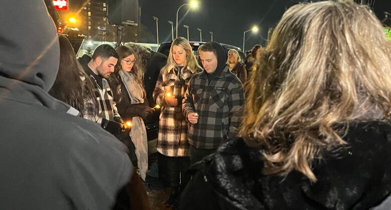 People hold candles on a cool winter night.