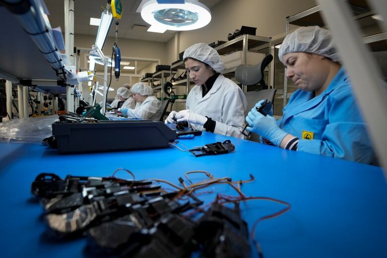 Women work on drones on an assembly line.