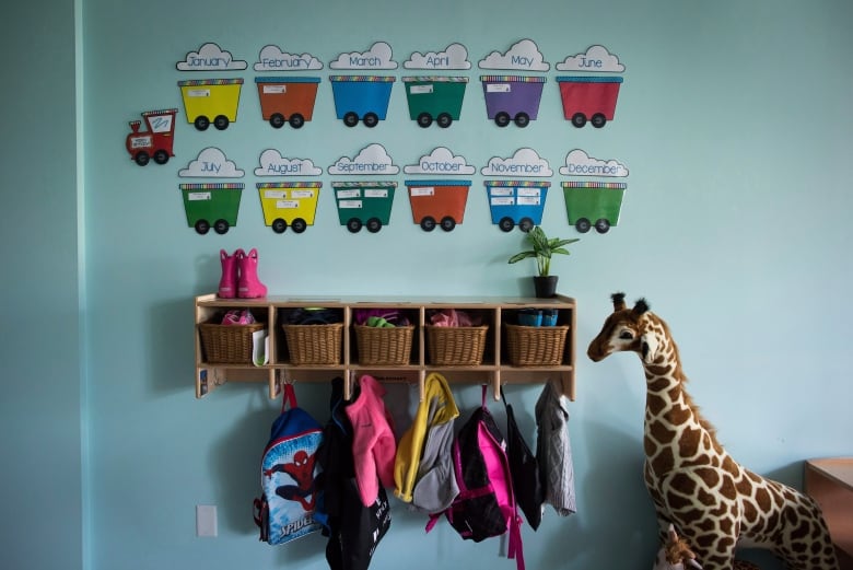 a wall features little month images made to look like a children's train. a stuffed giraffe and a bookshelf.