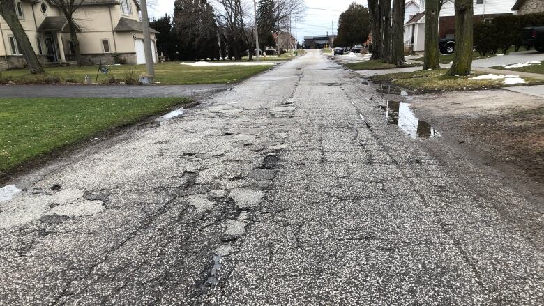 An old, neglected road with small puddles of water on the side