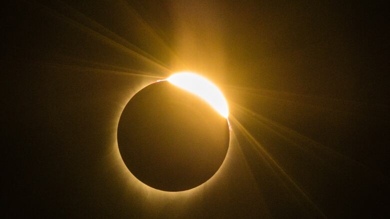 Black sky with orange ring of light as the sun is eclipsed by the moon.