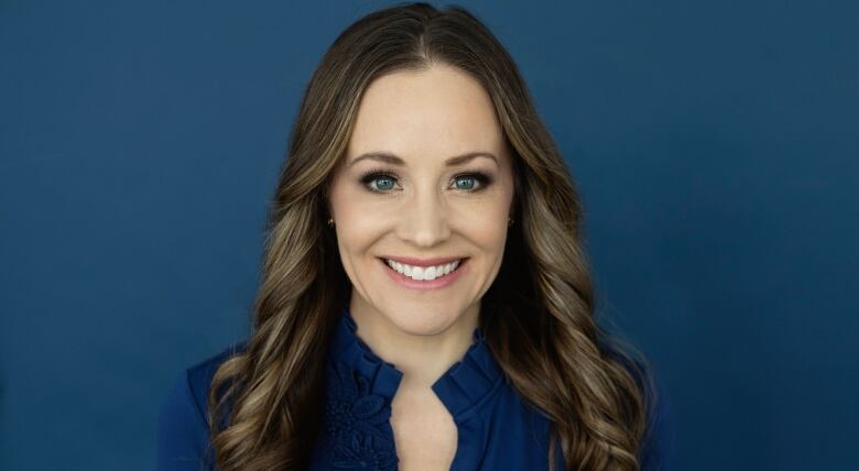 Woman with long brown hair smiles directly at the camera. 