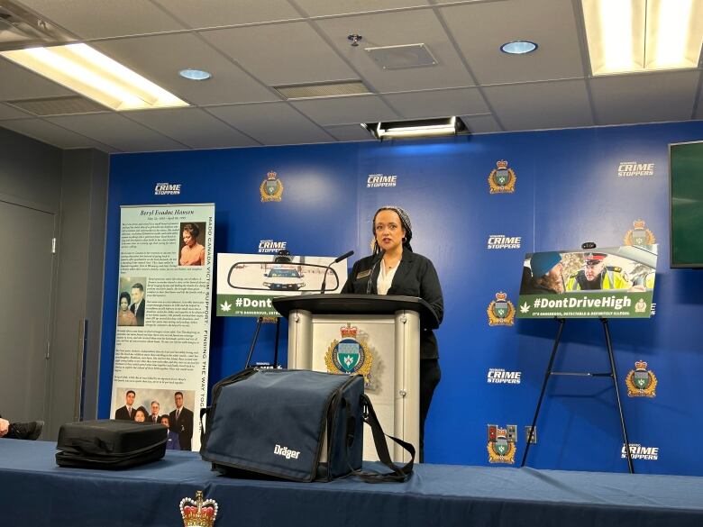 A woman in a black blazer and white shirt speaks into a microphone at a lectern during a news conference.