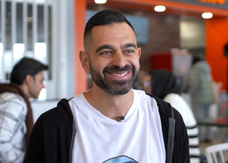 A man with a beard sitting in a university cafeteria.