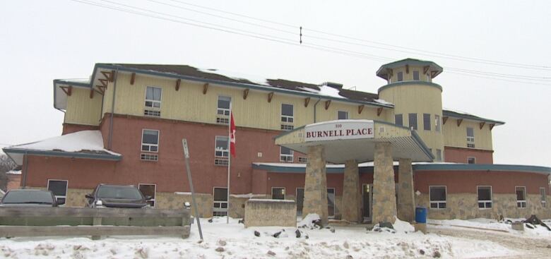 A brick and wood building with a tower, snow on the ground.