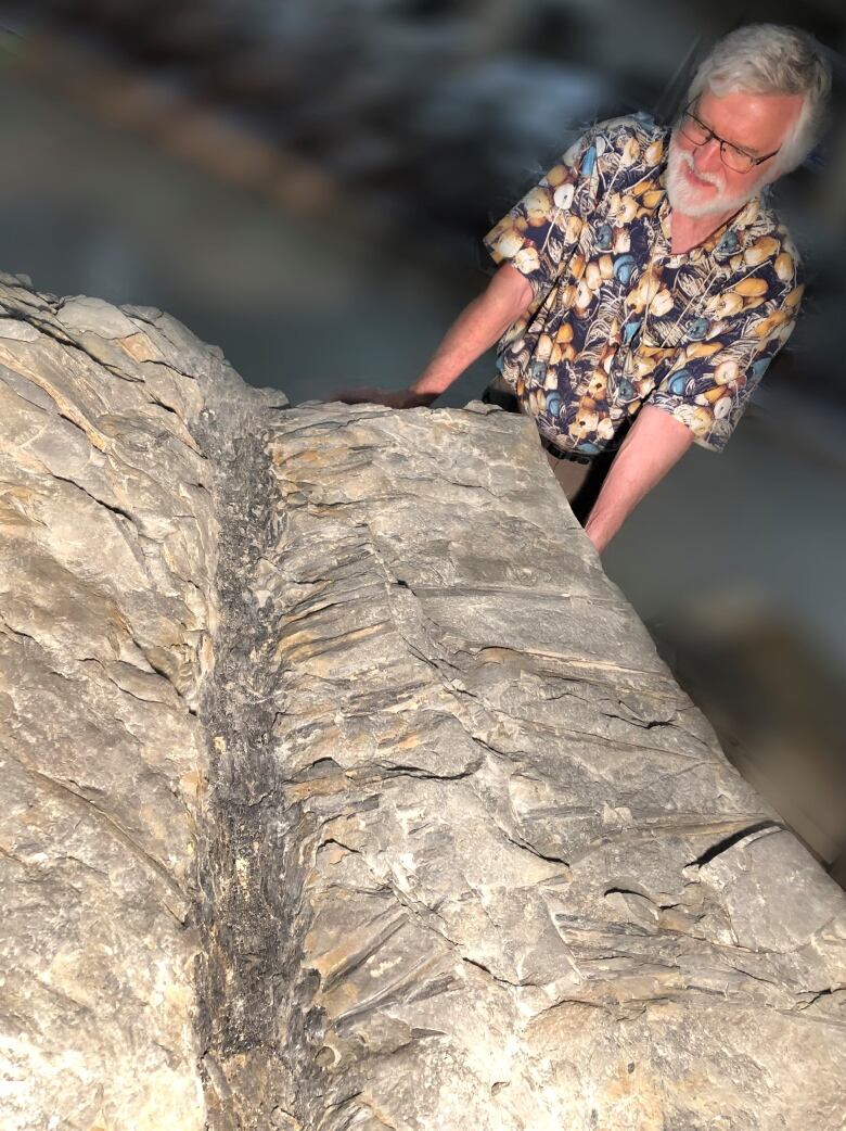 A man stands over a fossil