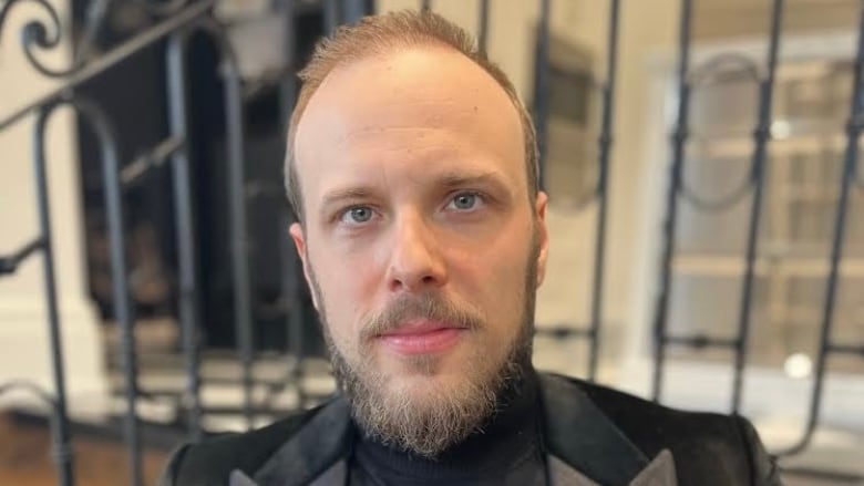 A close portrait of a bearded man in a suit jacket