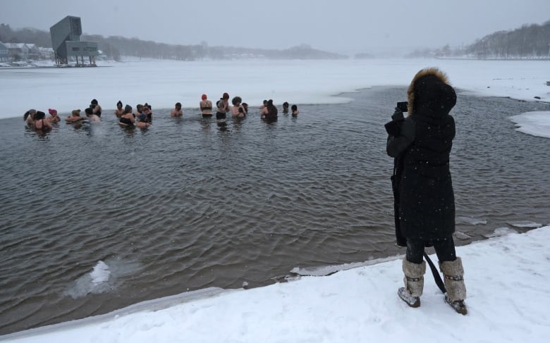 A woman photographs members of a polar bear swim club.