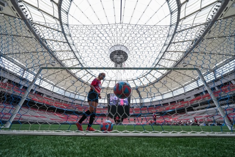 A low shot of a soccer stadium through a soccer net is displayed.