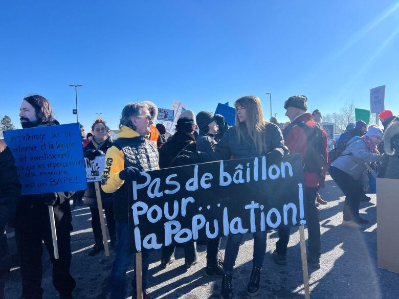 People are gathered outside with signs and banners.