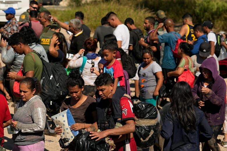 Dozens of people are seen in a long line in an outdoor setting.