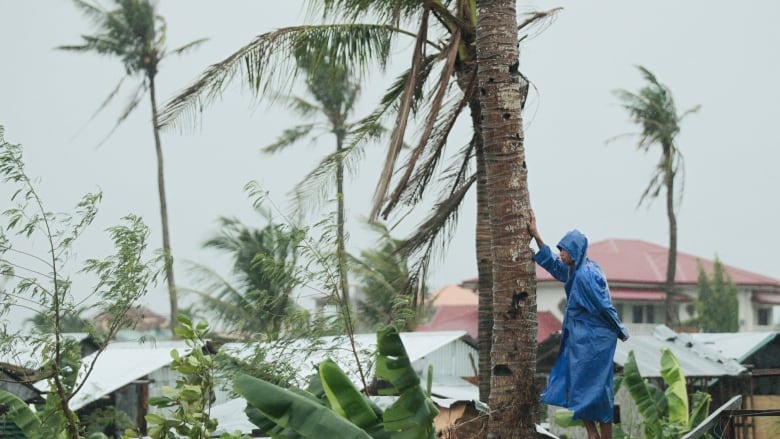 A Typhoon Haiyan survivor stands on top of wreckage