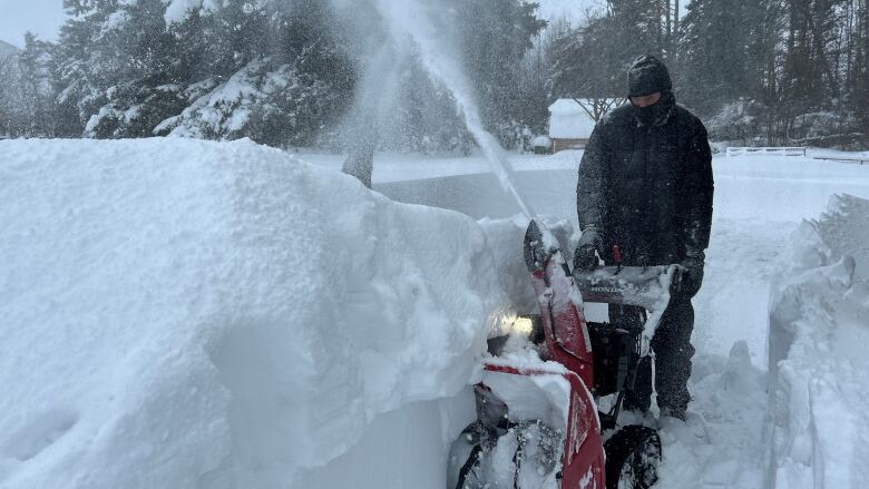 A person operating a snowblower through a deep drift of snow.