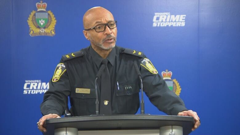 A man in a police uniform stands behind a podium.