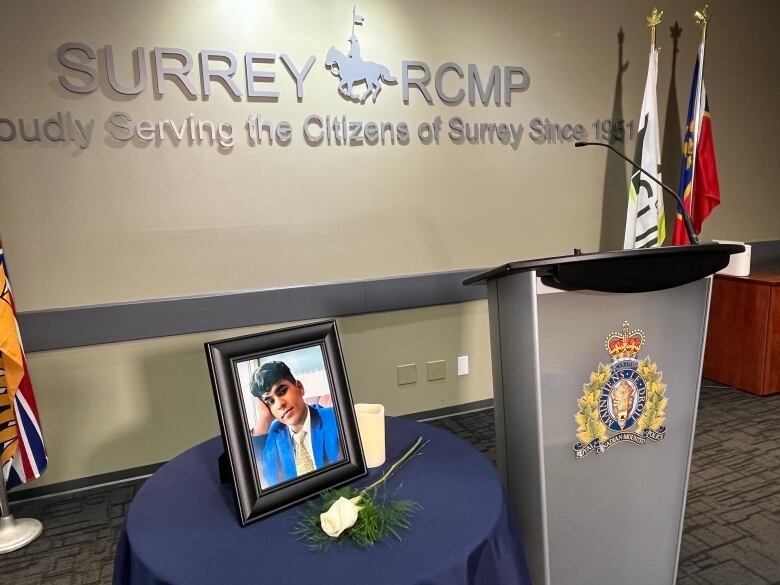 A framed photograph of a youth in a suit sits on a table with candles.