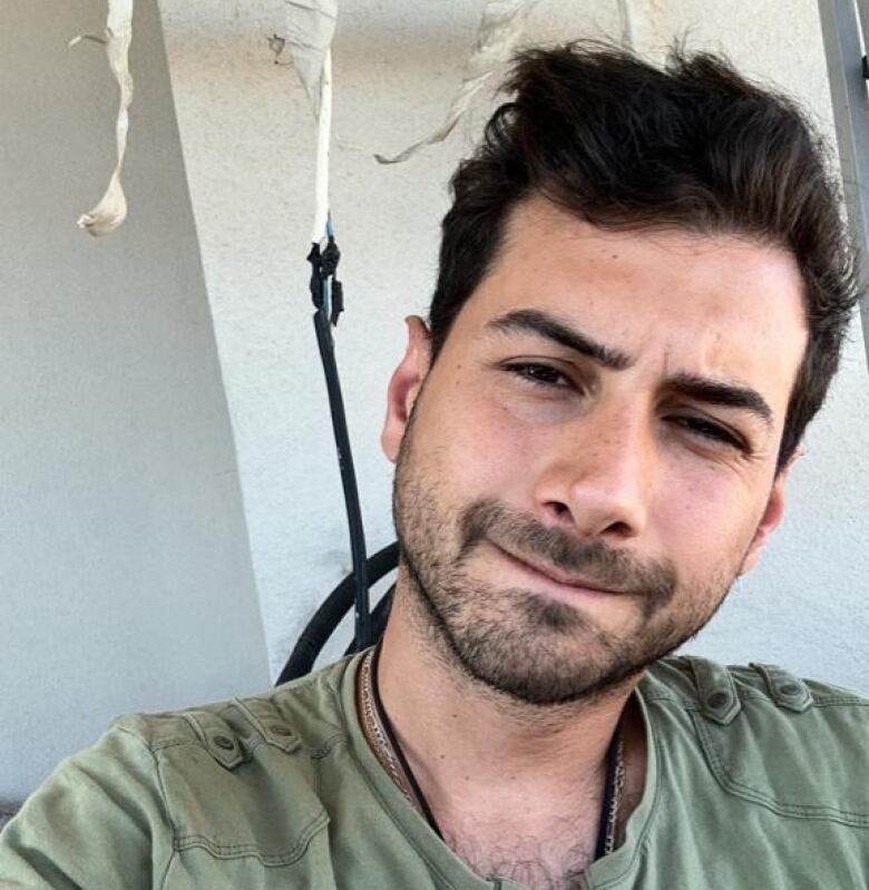 Selfie of a young man with dark hair, matching scruff and an army-green Henley-style T-shirt.