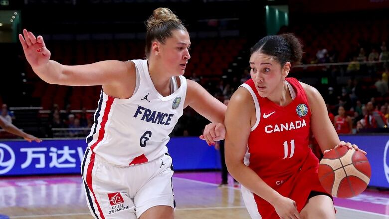 A basketball player dribbles the ball as an opponent defends.