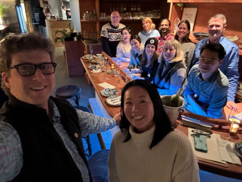 Two people take a selfie with a group tasting oysters 