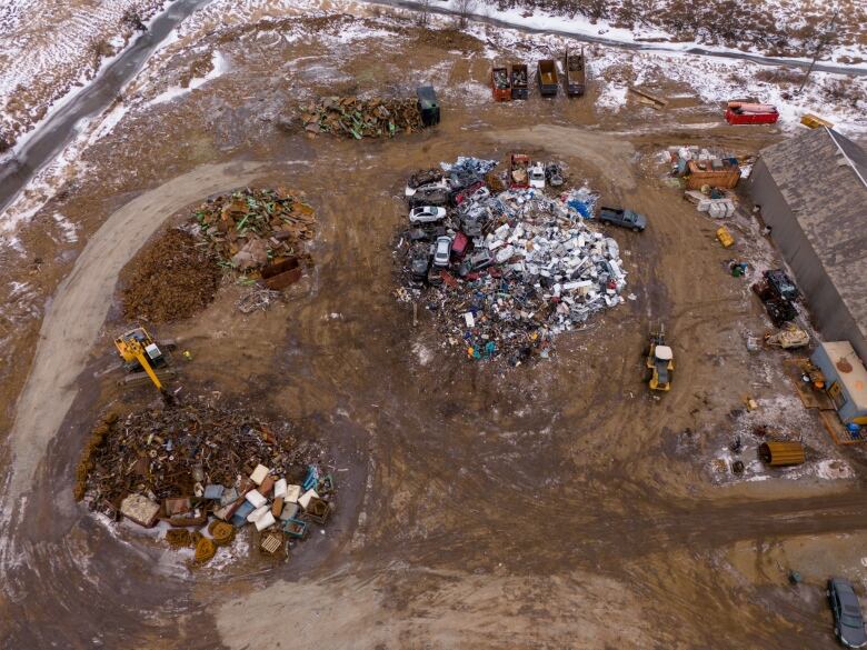 An overhead view of piles of scrap material with a yellow excavator and loader.