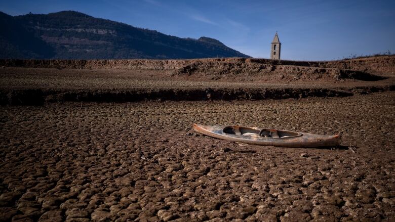 An empty canoe lies on a dirtbed.