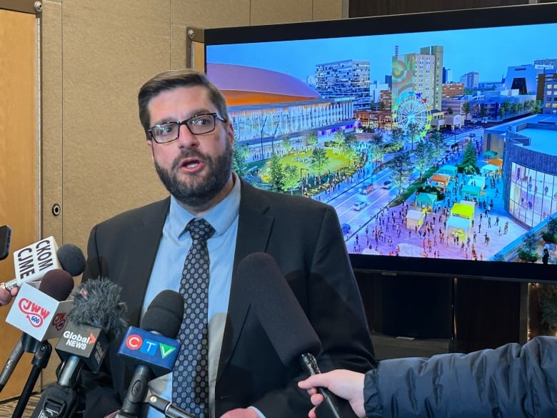 A man in a blue suit talking into microphones from different news media outlets.