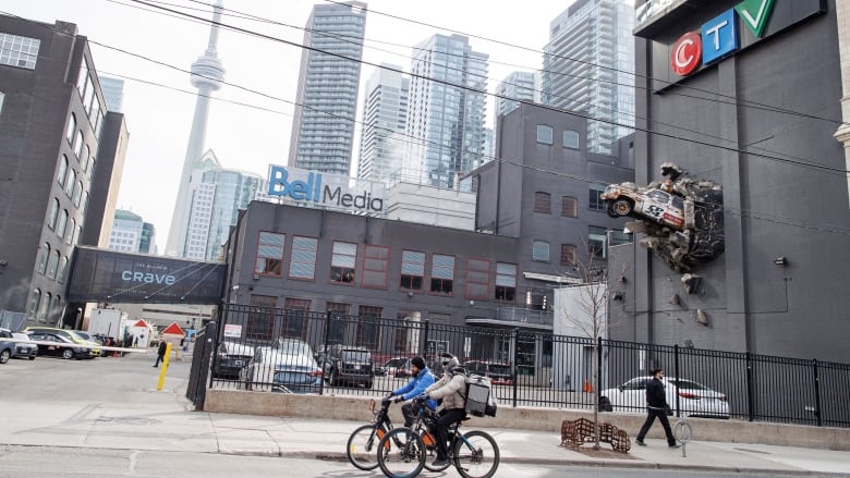 A building in downtown Toronto with Bell Media and CTV signage, and a model car with the CP24 logo on it crashing out of the side of the building.