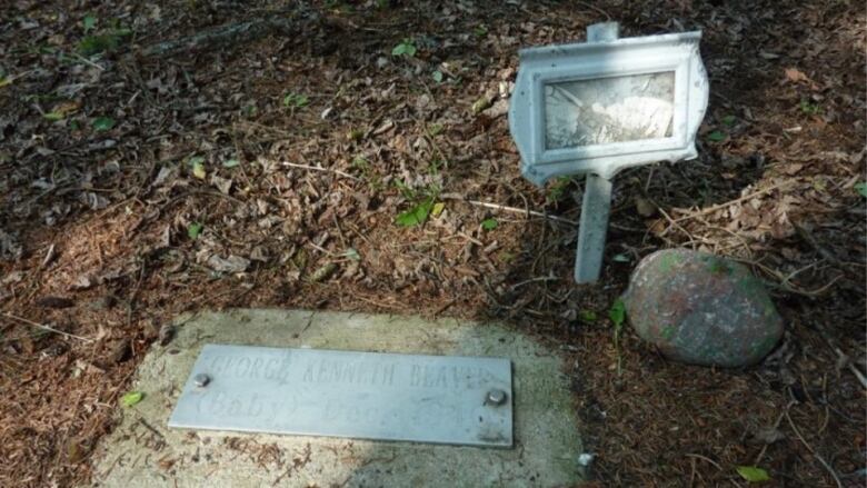 A small grave marker with the faded words George Kenneth Beaver.