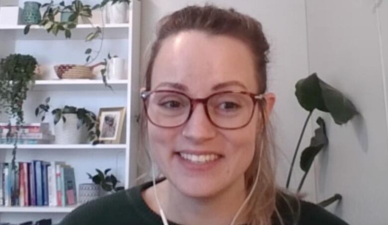 A woman smiles wearing glasses.