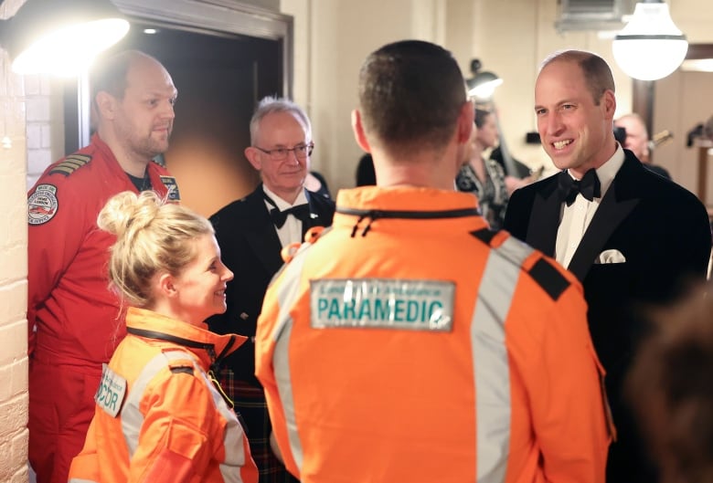 People wearing paramedic uniforms speak with a person.