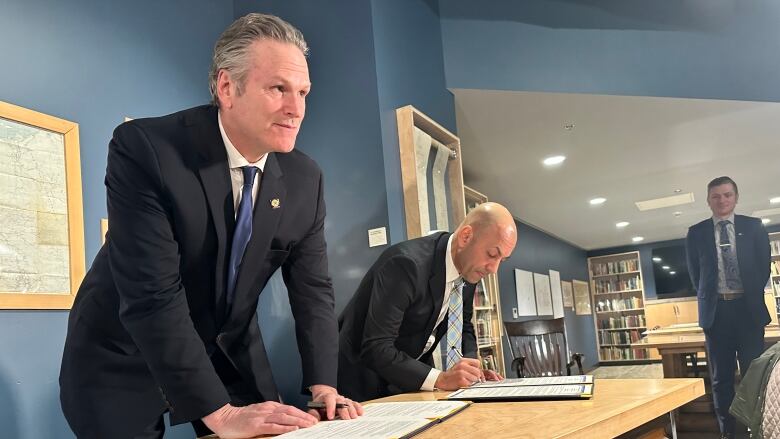 Two men sign a document.