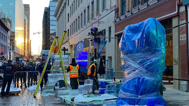 Ice sculptures stand wrapped in tarps meant to protect them from harmful weather conditions. 