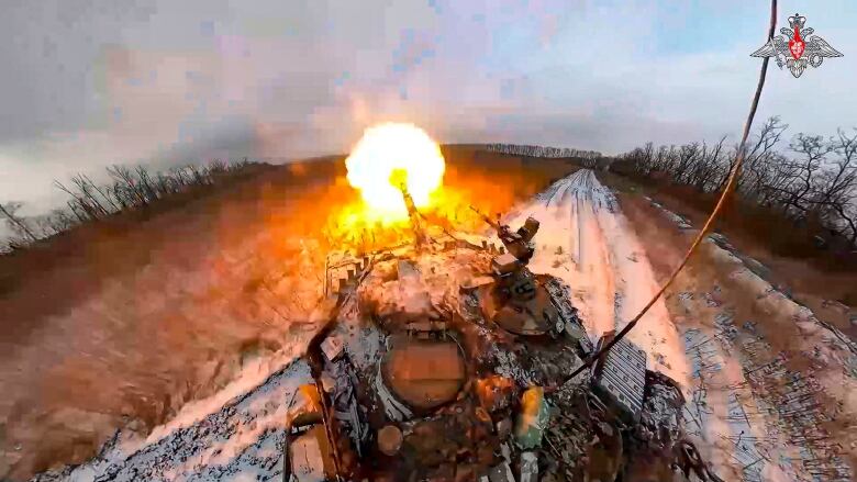 A tank fires a shell in a snow-covered field.